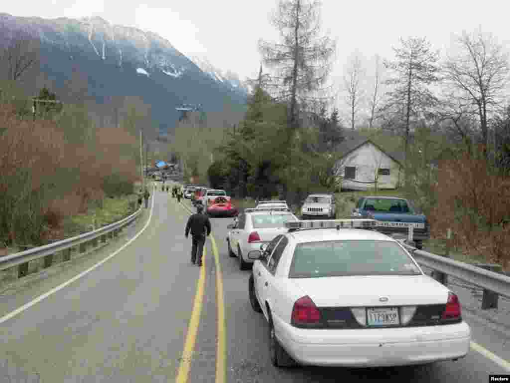 Officials and cars line the highway at the site of a large mudslide in this handout photo provided by the Washington State Police near Oso, Washington, March 22, 2014. 