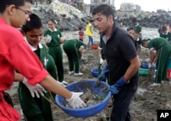 FILE - Afroz Shah, in black, participates in a clean up drive with school children at the Versova beach on the Arabian Sea coast in Mumbai, India.