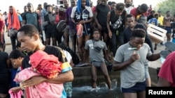 在美国寻求避难并等待在德克萨斯州德尔里奥接受审理的移民在墨西哥和美国之间的国际大桥附近的格兰德河洗浴。(2021年9月17日)