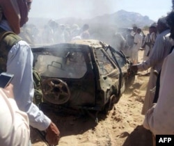 FILE - Yemenis gather around a burnt car after it was targeted by a drone strike, which killed three suspected al-Qaida militants, between Marib and Chabwa provinces, a desert area east of Sana'a, Jan. 26, 2015.