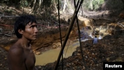 FILE - An Yanomami indian stands near an illegal gold mine during Brazil’s environmental agency operation against illegal gold mining on indigenous land, in the heart of the Amazon rainforest, in Roraima state, Brazil, April 17, 2016.