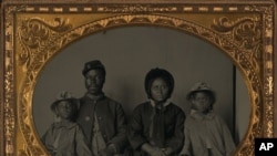 Unidentified African American soldier in Union uniform with wife and two daughters between 1863 and 1865.