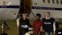 Medhane Tesfamariam Berhe is pictured with Italian policemen as they land at Palermo airport, Italy, following his arrest in Khartoum, Sudan, on May 24, in this file photo released June 8, 2016 by Italian police. Image pixelated at source.