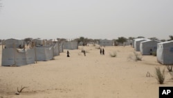 FILE - Nigerians who fled Boko Haram to Chad walk through the Baga Solo refugee camp in Chad, March 4, 2015.