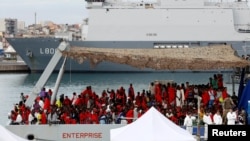 Des migrants attendent pour descendre du bateau de la Royal Navy Ship HMS Enterprise dans un port sicilien, Italie, le 23 octobre 2016.