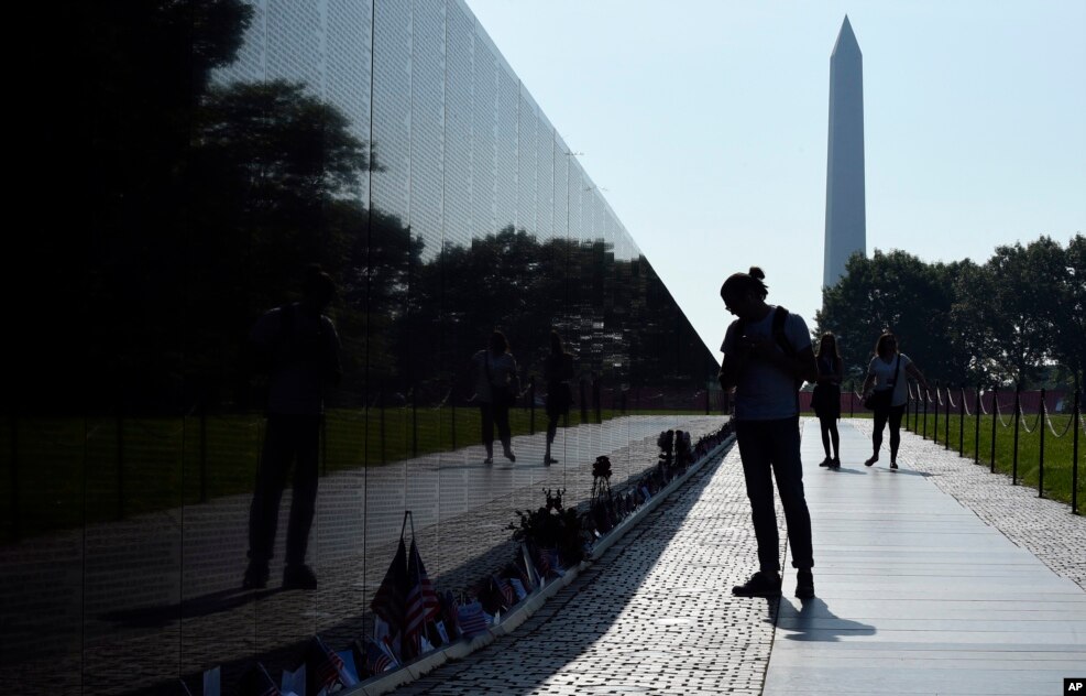 With the Washington Monument in the background, people visit the Vietnam Memorial in Washington on the start of the Memorial Day weekend.