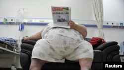 FILE - An obese person is seen reading a newspaper.