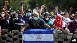 Manifestantes enmascarados protestan con bloqueos de calles en Managua cerca de la Universidad Politécnica de Nicaragua, el sábado, 21 de abril, de 2018.