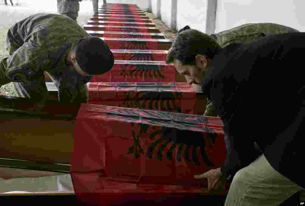Anggota pasukan keamanan Kosovo mengatur peti mati yang berisi jasad 24 orang Kosovo-Albania yang tewas dalam perang tahun 1998-99 dengan Serbia, di desa Merdare, Kosovo. Jasad-jasad tersebut ditemukan di kuburan massal Rudnica di Serbia dan diidentifikasi 15 tahun setelah perang. &nbsp;