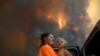 Sharnie Moren dan anaknya Charlotte memperhatikan kebakaran lahan dekat Nana Glen, Coffs Harbour, Australia, 12 November 2019.