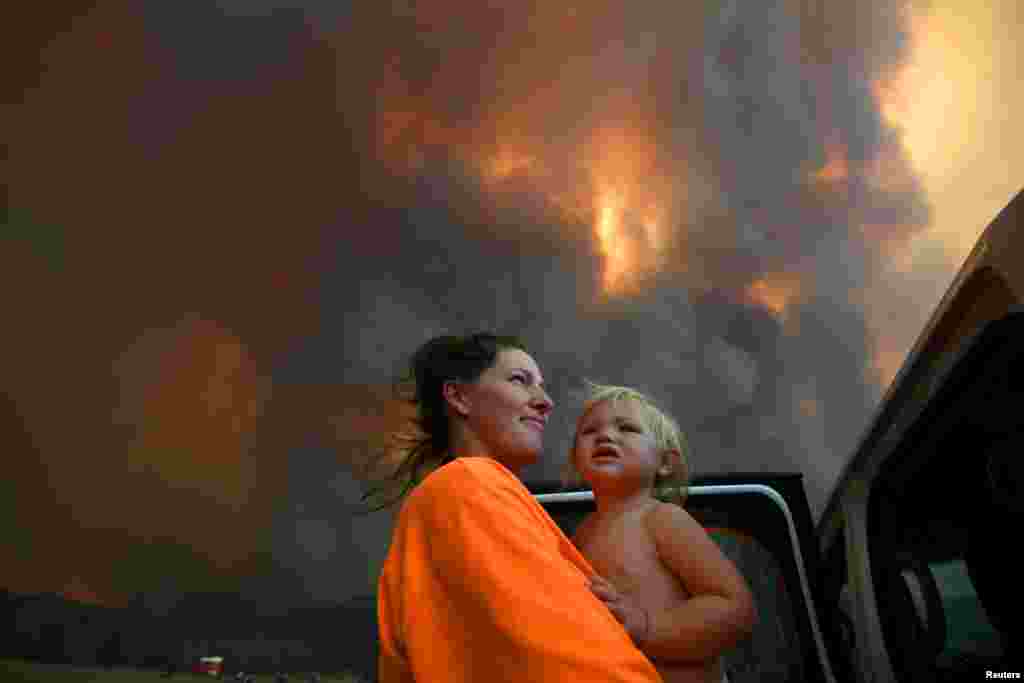 Sharnie Moren and her 18-month-old daughter Charlotte look on as thick smoke rises from bushfires near Nana Glen, near Coffs Harbour, Australia.