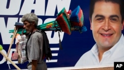 A street vendor walks past a campaign banner promoting National Party presidential candidate Juan Orlando Hernandez, in Tegucigalpa, Honduras, Nov. 23, 2013. 