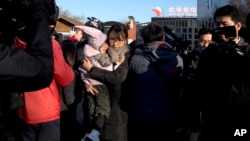 A woman leaves with a child after telling the media she came to withdraw the child from the RYB kindergarten in Beijing, China, Friday, Nov. 24, 2017. (AP Photo/Ng Han Guan)