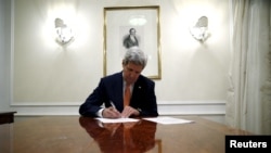 U.S. Secretary of State John Kerry signs a series of documents, including the certification to the U.S. government that International Atomic Energy Agency (IAEA) had certified Iran's compliance in their report and waivers to implement the lifting of the U.S. Congressional nuclear-related sanctions as outlined in the Joint Comprehensive Plan of Action.