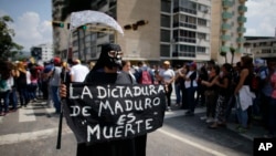A woman dressed in a grim reaper costume holds a sign that reads in Spanish: "Maduro's dictatorship is death" during a rally in Caracas, Venezuela, April 27, 2017.