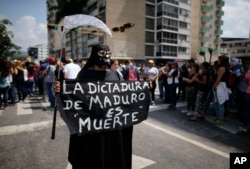 A woman dressed in a grim reaper costume holds a sign that reads in Spanish: "Maduro's dictatorship is death" during a rally in Caracas, Venezuela, April 27, 2017.