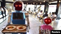 Sepasang robot membawa nampan makanan di sebuah restoran sebagai ilustrasi. Restoran White Fox di Mosul, Irak, menjadi sorotan, bukan karena suasana yang nyaman atau makanan dan minuman yang lezat, melainkan pelayannya. (Foto: Reuters)