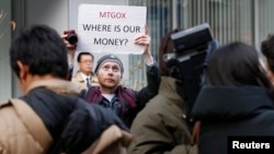 Kolin Burges, a self-styled cryptocurrency trader and former software engineer from London, holds up a placard to protest against Mt. Gox, in front of the building where the digital marketplace operator was formerly housed in Tokyo, Japan, Feb. 26, 2014. 