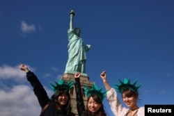 Japanese tourists pose in front of the Statue of Liberty on the 130th anniversary of the dedication in New York Harbor, in New York City, Oct. 28, 2016.