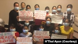 Những người phụ nữ Việt Nam cầm bảng kêu cứu trong một cơ sở tạm trú dành cho lao động nước ngoài gặp khốn khó ở Riyadh, Ả-rập Saudi. Nhiều người trong số này nói họ bị chủ lao động hành hạ.