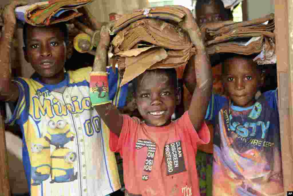 Children carry books damaged by the cyclone at a camp for displaced survivors of cyclone Idai in Dombe, about 280km west of Beira, Mozambique.