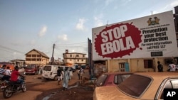 FILE - People pass a banner reading "STOP EBOLA" forming part of Sierra Leone's Ebola-free campaign in Freetown, Jan. 15, 2016.