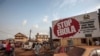 People pass a banner reading "Stop Ebola," forming part of Sierra Leone's Ebola-free campaign in the city of Freetown, Sierra Leone, Jan. 15, 2016.