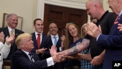 President Donald Trump shakes hands with Charles Robel after signing an executive in the Roosevelt Room of the White House in Washington, June 15, 2017, during an event on Apprenticeship and Workforce of Tomorrow initiatives.