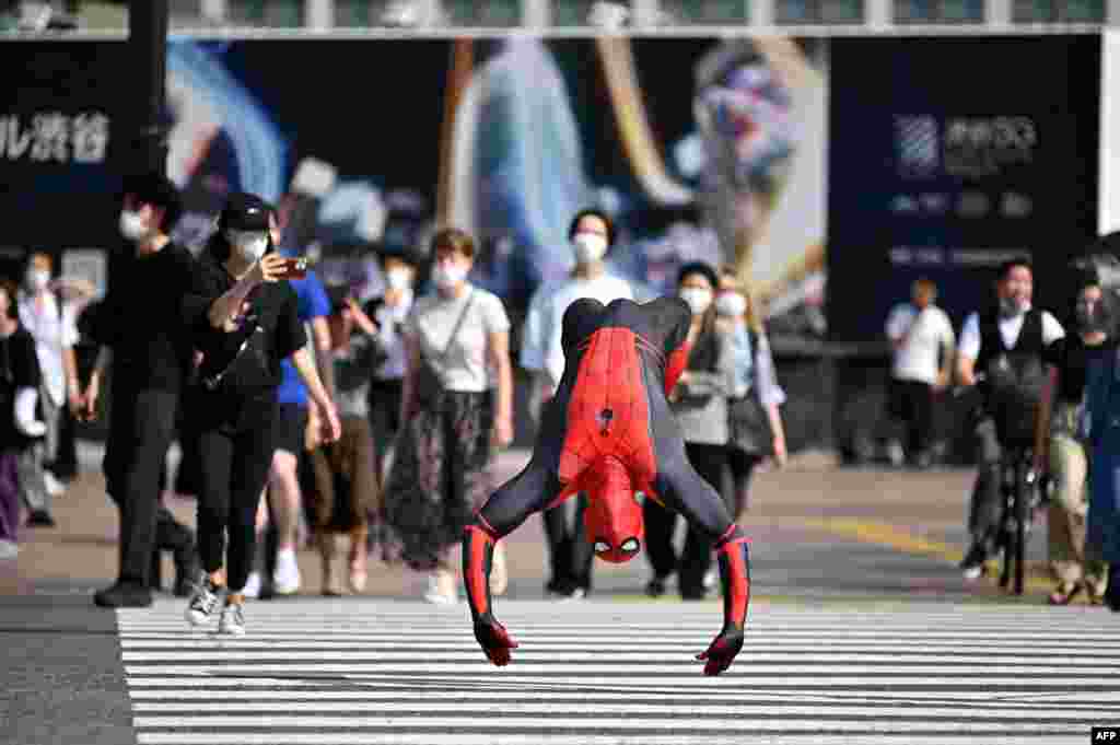 A man wearing a Spiderman costume jumps across Shibuya crossing in Tokyo, Japan.