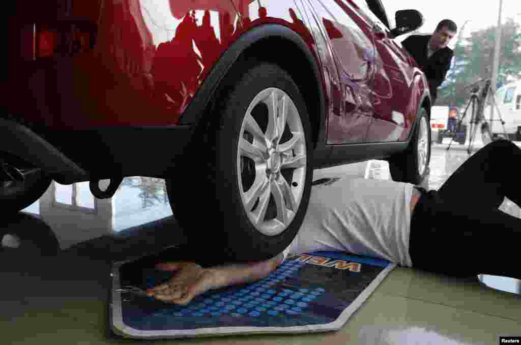 Norik Yajian reacts as a four-wheel car drives over his arm during his attempt to break a Guinness record in Tbilisi, Georgia.