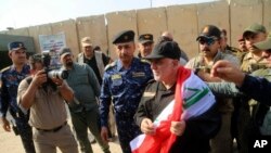Iraq's Prime Minister Haider al-Abadi, center, holds a national flag upon his arrival to Mosul, Iraq, July 9, 2017.