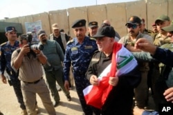 Iraq's Prime Minister Haider al-Abadi, center, holds a national flag upon his arrival to Mosul, Iraq, July 9, 2017.