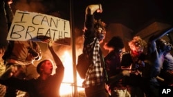 Protesters demonstrate outside of a burning Minneapolis 3rd Police Precinct, May 28, 2020, in Minneapolis. Protests over the death of George Floyd, a black man who died in police custody Monday, broke out in Minneapolis for a third straight night. (AP Photo/John Minchillo)