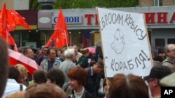 A Russian demonstrator holds sign with caricature of Vladimir Putin and the message: "We will throw the rat off the ship!" during a protest in Moscow, May 6, 2012. 