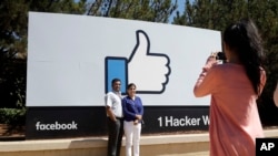 Pengunjung berfoto di depan logo fitur 'like' Facebook di depan kantor pusatnya di Menlo Park, California. (Foto: Dok)