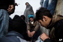 A group of Afghan refugees warm themselves near a fire at at the railway station of Sid, Serbia, where Serbian authorities send them to Croatia, Nov. 6, 2015.