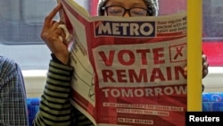 A woman reads a newspaper on the underground in London with a 'vote remain' advert for the BREXIT referendum, Britain June 22, 2016.