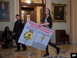 A Democratic aide carries a chart past the Senate chamber to be used by the minority to argue against the Republican tax bill, on Capitol Hill in Washington, Friday night, Dec. 1, 2017.