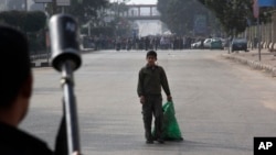 A boy looks at Egypt's security forces as they try to disperse supporters of ousted President Mohamed Morsi in Cairo, Egypt, Friday, Jan. 17, 2014.