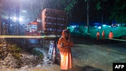 A Thai policeman guards an area under rainfall near the Tham Luang cave at the Khun Nam Nang Non Forest Park in Mae Sai district of Chiang Rai province, July 7, 2018, as the rescue operation continues for the 12 boys and their soccer coach.