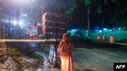 A Thai policeman guards an area under rainfall near the Tham Luang cave at the Khun Nam Nang Non Forest Park in Mae Sai district of Chiang Rai province, July 7, 2018, as rescue operation continues for the 12 boys and their football team coach.