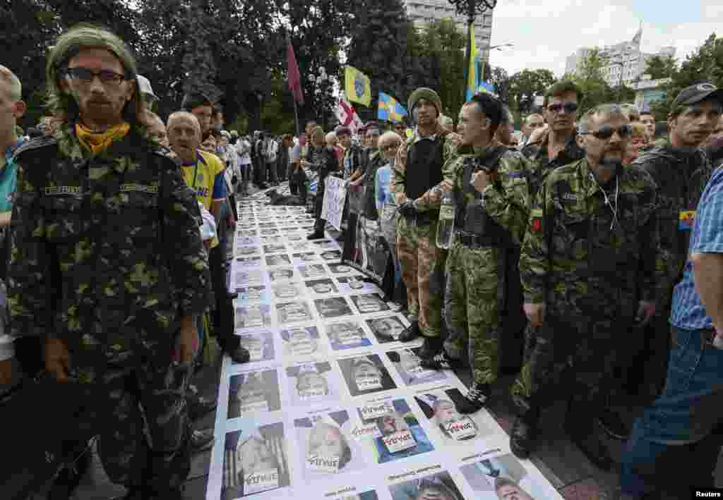 Members of a self-defense unit from the Maidan protests construct a &quot;corridor of shame&quot; at the entrance to parliament made up of portraits of Ukrainian deputies from the Party of Regions and Communist Party laid out on the ground outside the assembly in K