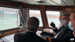 In this photo released by the Suez Canal Authority, Lt. Gen. Ossama Rabei, head of the Suez Canal Authority, second right, speaks to other staff onboard a boat near the stuck cargo ship Ever Given on Wednesday, March 24, 2021.