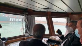 In this photo released by the Suez Canal Authority, Lt. Gen. Ossama Rabei, head of the Suez Canal Authority, second right, speaks to other staff onboard a boat near the stuck cargo ship Ever Given on Wednesday, March 24, 2021.
