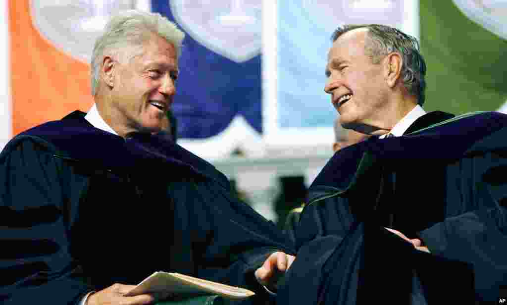 Former Presidents Bill Clinton, left, and George H. W. Bush smile at each other on the podium at the Tulane University Commencement in New Orleans, Louisiana, May 13, 2006. 