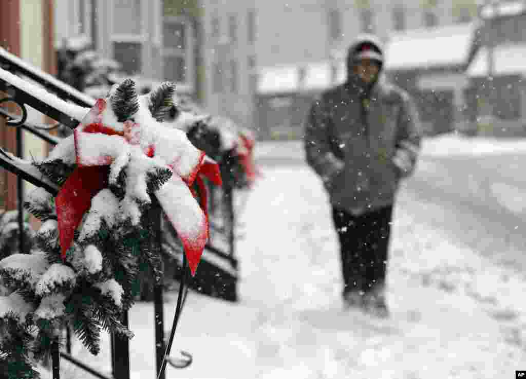 A man walks past snow-covered Christmas decorations on apartments in Berea, Ohio, December 26, 2012. 