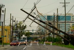 Kendaraan dialihkan di sekitar tiang listrik yang ambruk akibat diterjang Badai Ida, di New Orleans, Louisiana, Selasa, 31 Agustus 2021. (Foto AP/Eric Gay)