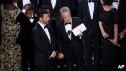 Presenter Warren Beatty shows the envelope with the actual winner for best picture as host Jimmy Kimmel, left, looks on at the Oscars on Sunday, Feb. 26, 2017, at the Dolby Theatre in Los Angeles. The winner was originally announced as "La La Land," but w