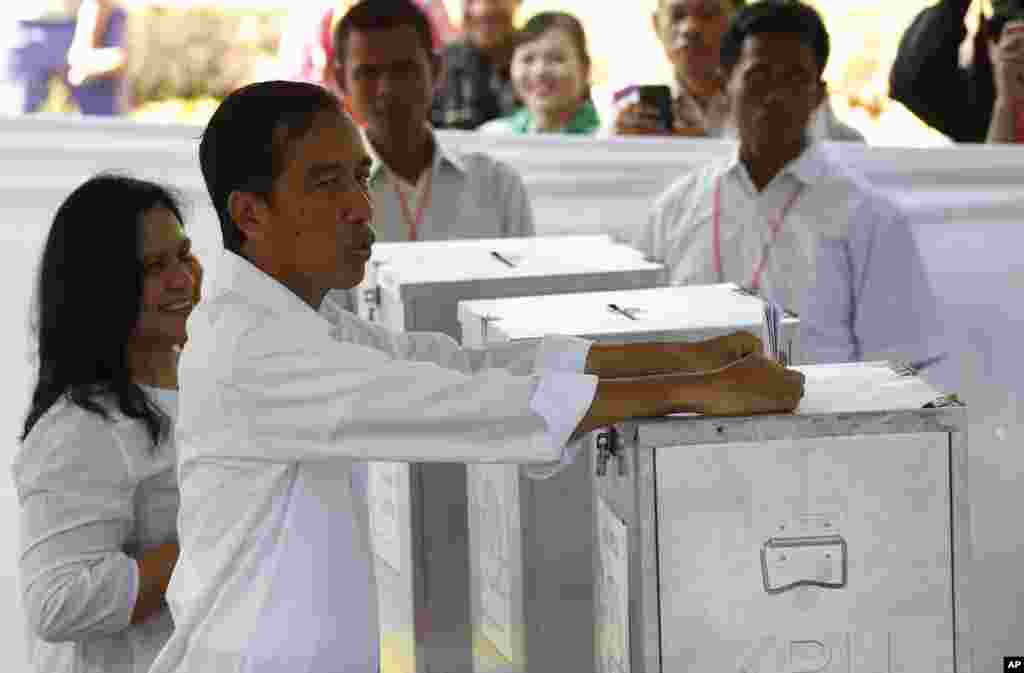 Presidential candidate Joko Widodo, front, casts his ballot next to his wife Iriana Joko Widodo at a polling station in Jakarta, April 9, 2014.