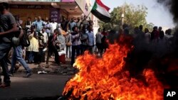 FILE - People chant slogans and burn tires during a protest to denounce the October 2021 military coup, in Khartoum, Sudan, Jan. 6, 2022.